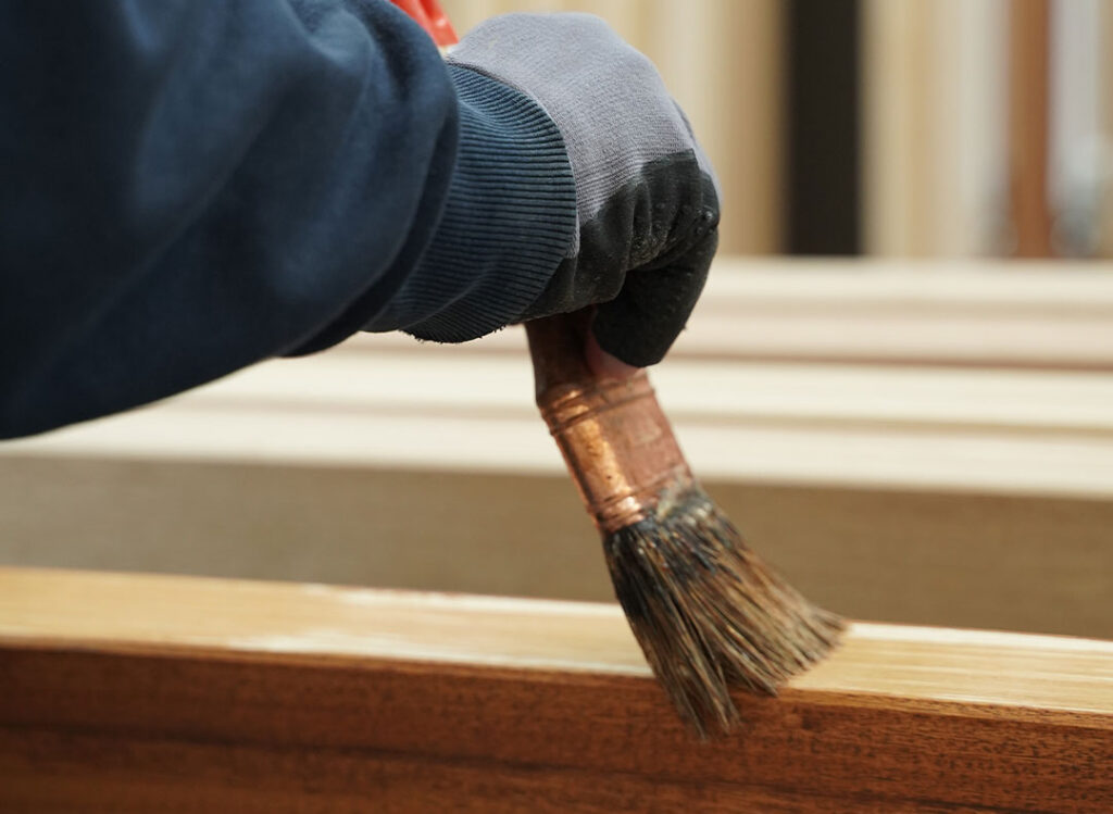 mano che vernicia legno con un pennello